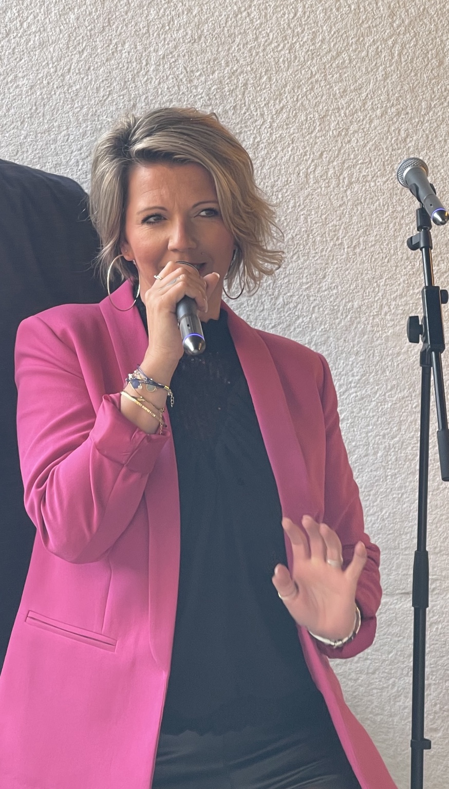 Nelly Dulac chante au micro en veste rose